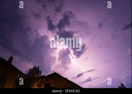 Flash of lightning above houses in southeastern France in the evening Stock Photo