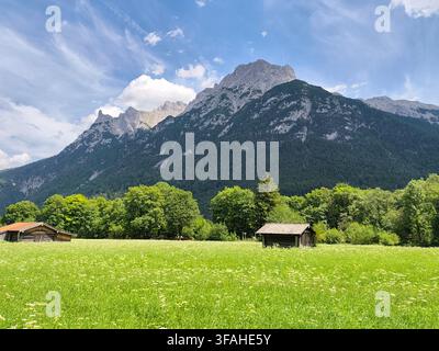 Scenic summer landscape with a small wooden hut in a lush green meadow beneath the majestic Karwendel mountains in Mittenwald, Bavaria, Germany Stock Photo