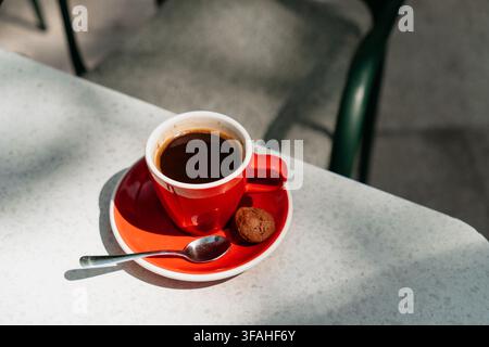 Fresh americano served in a red ceramic cup with cookie on a bright table. Smooth flavor and premium coffee moment create a stylish cafe lifestyle Stock Photo