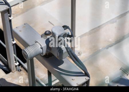 Close-up view of a gray metal industrial valve actuator mechanism with a handwheel and connected wiring Stock Photo