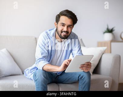 Handsome Young Arab Man Using Digital Tablet Computer At Home Stock Photo