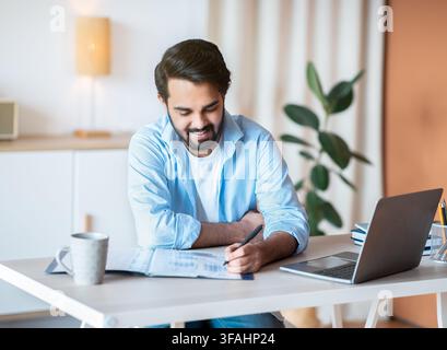 Smiling Arab Man Working With Documents And Laptop At Home Office Stock Photo