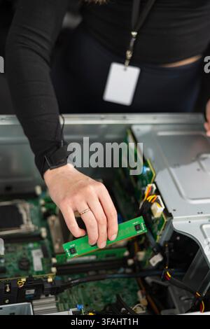 Female IT technician in her 30s upgrades a server with a new PCIe expansion card Stock Photo
