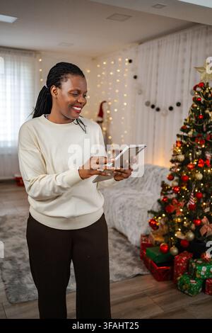 Smiling black woman using tablet during Christmas holidays Stock Photo