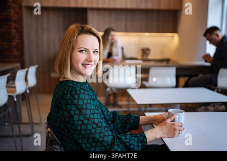 Smiling business woman having coffee break in office Stock Photo