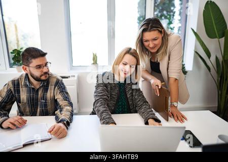 Business team collaborating on project using laptop in office Stock Photo