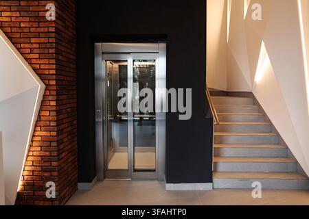 Modern interior featuring elevator and staircase with geometric lighting Stock Photo