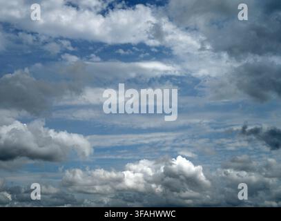 Horizontal view of a mostly cloudy sky with blue patches and light and dark clouds along with mid tone clouds Stock Photo