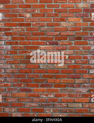 Weathered red brick and mortar wall surface with varied red bricks, occasional tan bricks, aged and worn bricks with cracks Stock Photo