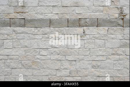 Horizontal view of sawn brick and mortar wall surface with rough cut uneven brick faces, porous texture, broken and chipped masonry Stock Photo