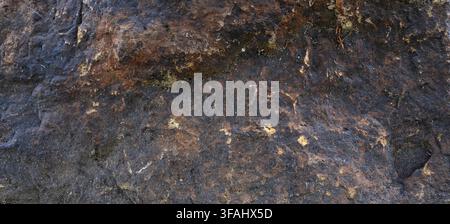Porous, rough boulder surface with uneven texture and natural ridges and crevasses showing mineral coloration Stock Photo