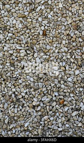 Vertical view of small multi‑stone wall surface with assorted stones in varied shapes, colors, and sizes set in a cement mixture Stock Photo