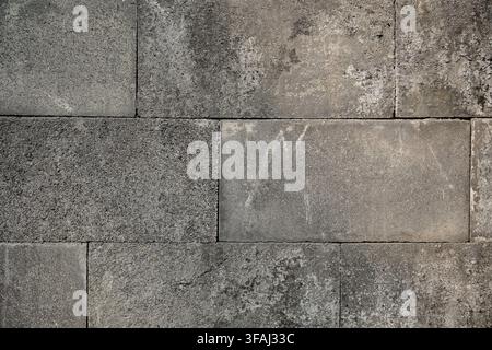 Close up of a weathered grey concrete block wall showing rough texture, grunge details, and natural wear. Perfect for architectural backgrounds. Stock Photo