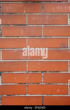 Close up view of a classic red brick wall with visible grout lines and slight weathering. Ideal for architectural backgrounds, urban backdrops. Stock Photo