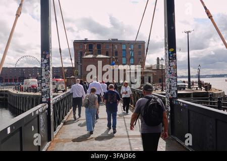 Pedestrians, walking across the modern swing bridge connecting Mann Island and Royal Albert Dock in Liverpool, UK. Stock Photo