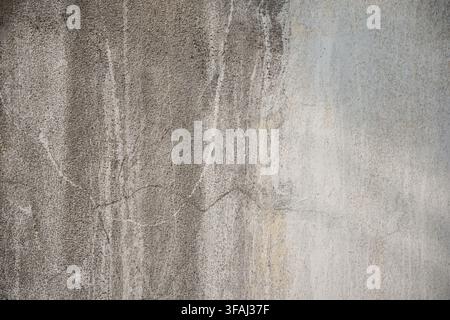 Close up of an old grey concrete wall featuring a distinct horizontal crack and natural water streaks. Shows a rough. Stock Photo