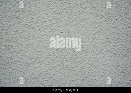 Close up of a white exterior wall with a heavy, bumpy roughcast stucco finish. A clean, uniform architectural texture ideal for blank backdrops. Stock Photo
