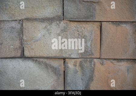 Close up view of a natural sandstone block wall with varying shades of brown, tan, and grey. A solid masonry texture ideal for architectural. Stock Photo