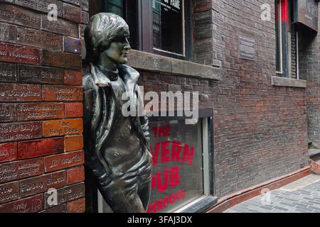 The life-size bronze statue of John Lennon leaning against a brick wall engraved with musicians names outside The Cavern Pub in Liverpool, UK Stock Photo