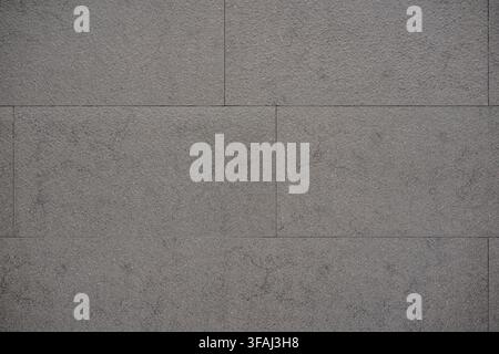 Close up of a smooth dark grey stone tile surface. A clean, uniform architectural background texture showing rectangular concrete. Stock Photo