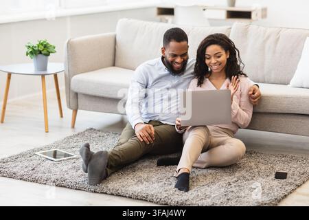 Black couple having videocall using laptop waving hands Stock Photo