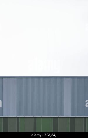 Abstract minimalist exterior shot of an industrial building wall showing blue corrugated metal cladding above green vertical panels. Stock Photo