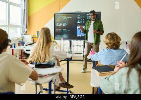 Indian Teacher Explaining Coding to Teenagers in Classroom Stock Photo