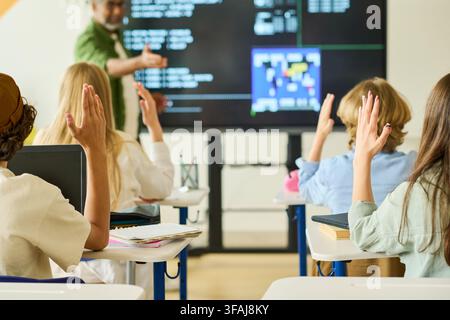 Teenagers Raising Hands in Computer Science Class with Teacher Stock Photo