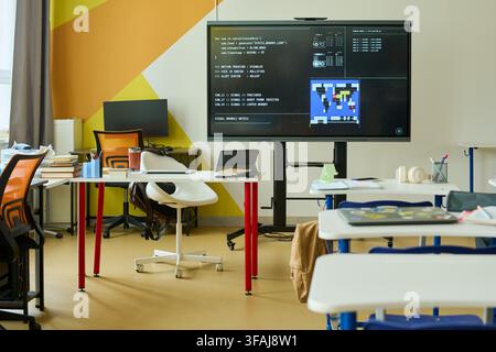Empty Modern Classroom with Coding Software on Interactive Screen Stock Photo