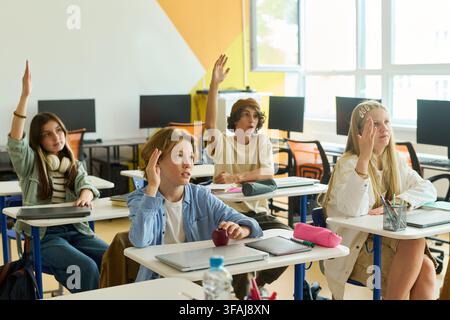 Teenagers Raising Hands in Computer Science Classroom Stock Photo