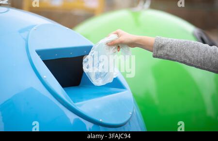 Zero Waste. Woman throwing single use plastic bag into blue recycle bin Stock Photo