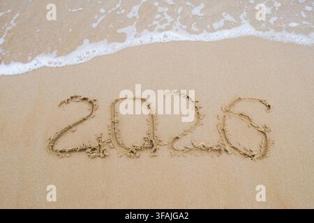 The inscription 2026 on the sand by the sea. Happy New Year. Stock Photo