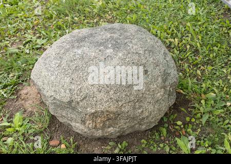 Large round granite boulder on green grass field. Stock Photo