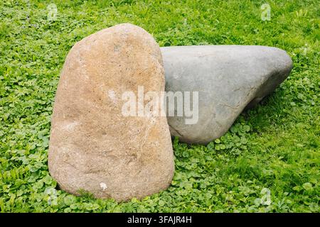 Two large natural stone boulders on green grass lawn. Stock Photo