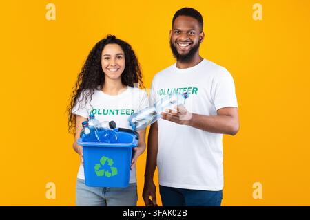 Two Volunteers Holding Box Full Of Plastic Bottles In Studio Stock Photo
