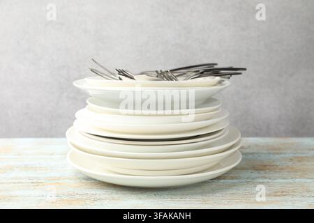 Ceramic dishware and cutlery on wooden table against gray background Stock Photo