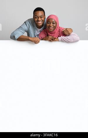 Cute african american couple leaning on white empty board Stock Photo