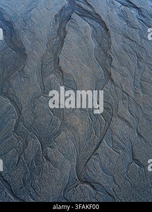 Minimalist sand surface showing organic vein-like patterns formed by water erosion. Soft grey natural texture ideal for abstract backgrounds. Stock Photo