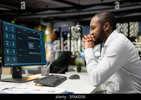 African american expert programming software code on desktop pc, using coding language for debugging tasks. Workspace with modern tech helps with engineering and web development. Stock Photo