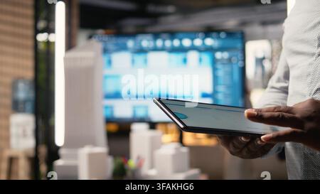 Close up of black professional uses architectural software on tablet to create plan for a smart city infrastructure, focusing on property construction, investment and zoning regulations. Stock Photo
