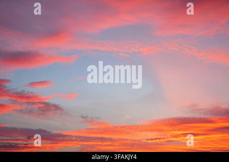Spectacular twilight sky background at sunset or sunrise with dramatic colorful clouds in shades of pink, orange, red and light blue Stock Photo