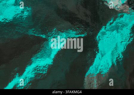 Dark cyan textured glass surface with glowing patterns in a studio. Stock Photo