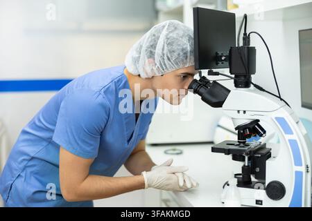 Attentive young male doctor looks through microscope in laboratory department of veterinary clinic Stock Photo