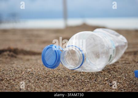 Plastic bottle lies on sandy beach near the shore Stock Photo
