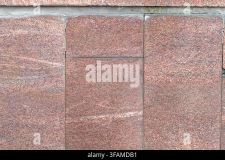Intricate details are revealed in the patterns of pink granite blocks, showcasing their unique textures and hues, harmoniously blending with the rusti Stock Photo