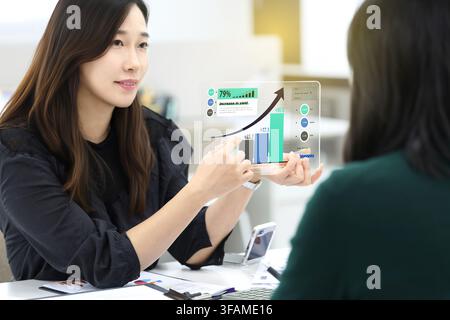 Korean Businesswoman Presenting a Digital Business Growth Chart to a Client Stock Photo