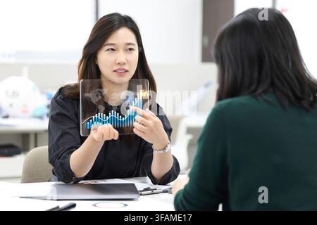 Korean Businesswoman Presenting a Digital Business Growth Chart to a Client Stock Photo