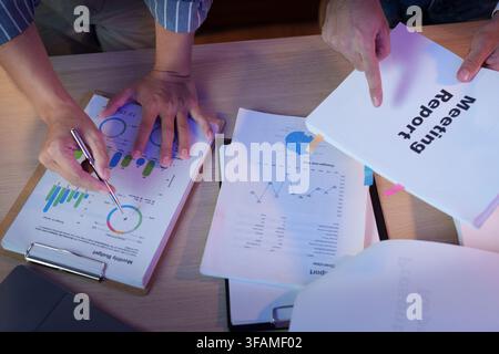 Business team analyzing financial reports on desk while working late overtime Stock Photo