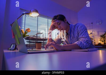 Tired Asian businessman resting head while working late at office desk Stock Photo