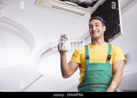 Young mechanic repairs ceiling air conditioner Stock Photo